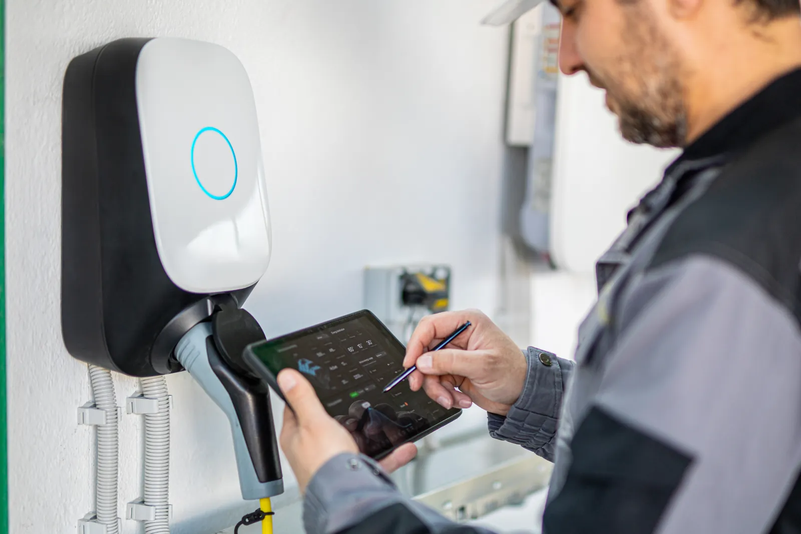 Technician testing a wall-mounted EV charger with a tablet