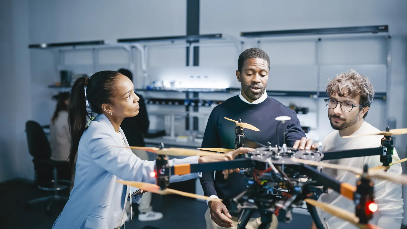 Engineers examining a large multirotor drone on a lab bench